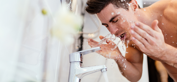 Handsome young man splashing water on his face