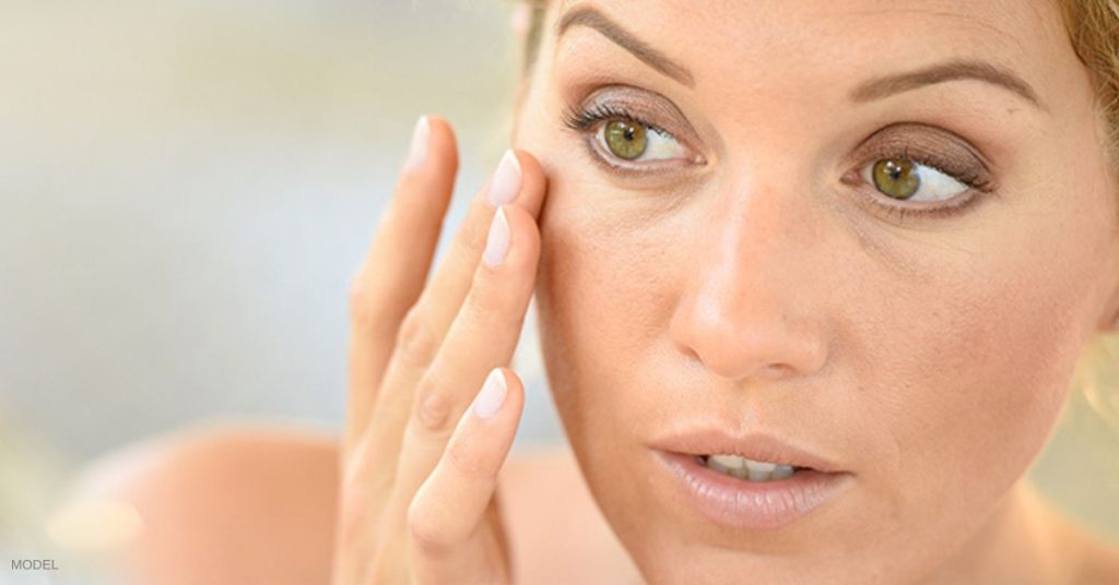 Woman (model) holding a hand under her face.