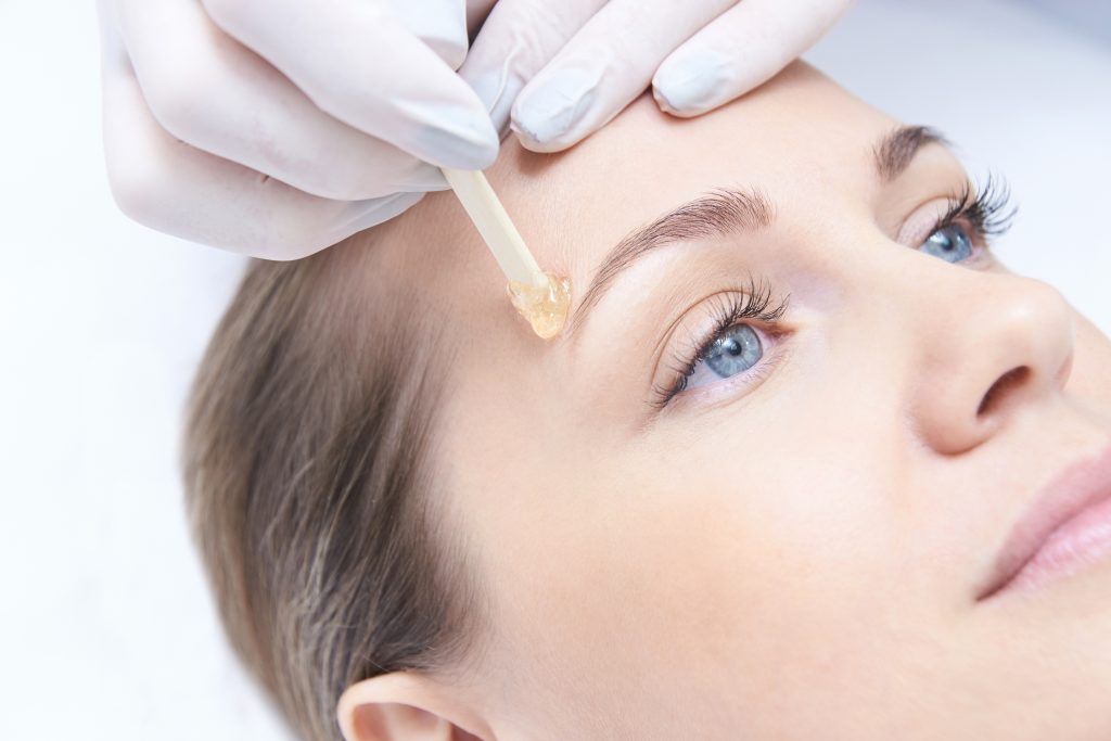 young woman getting eyebrows waxed (model)