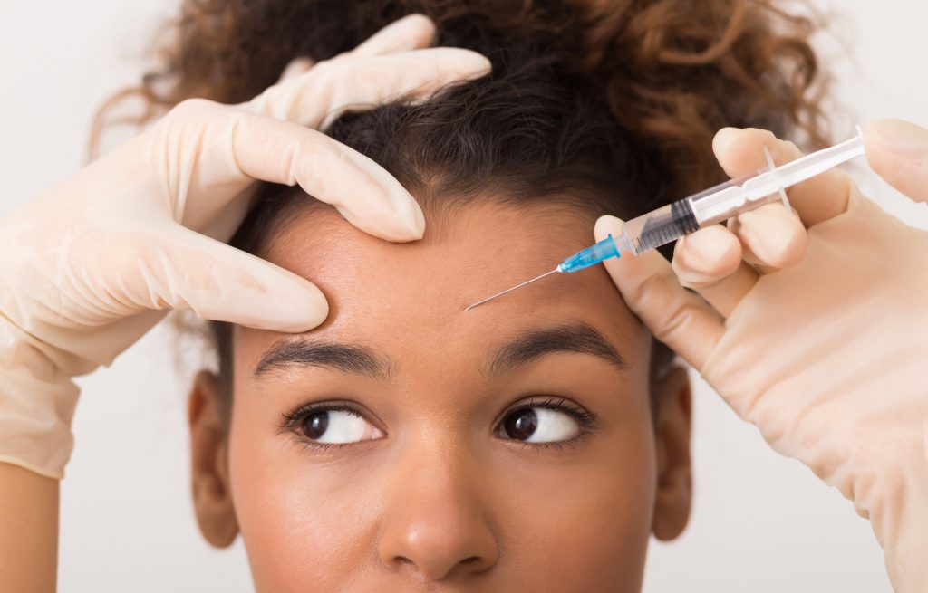 African american woman getting Botox injected into her forehead