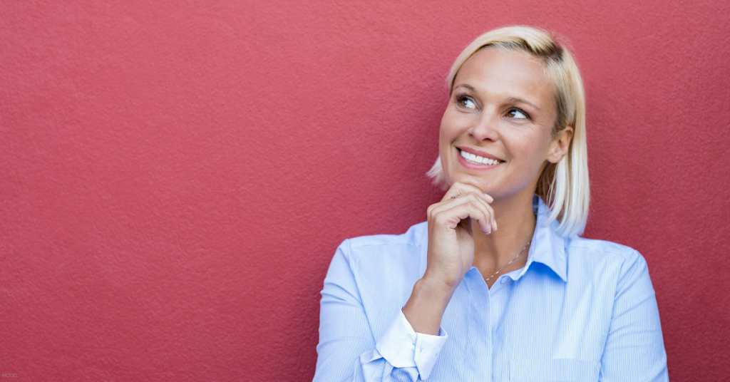 A woman poses against a red wall.