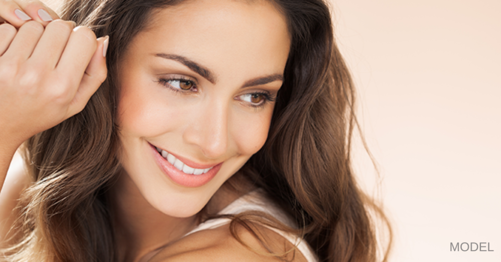 Attractive young woman with beautiful skin smiling and looking down and to right (model)