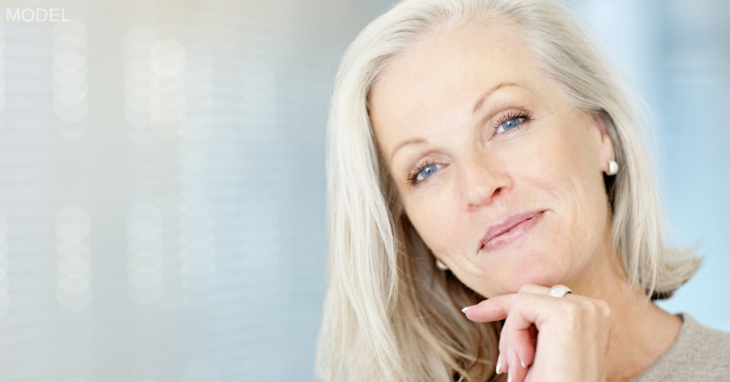 Older woman smiling with her hand on her chin (model)