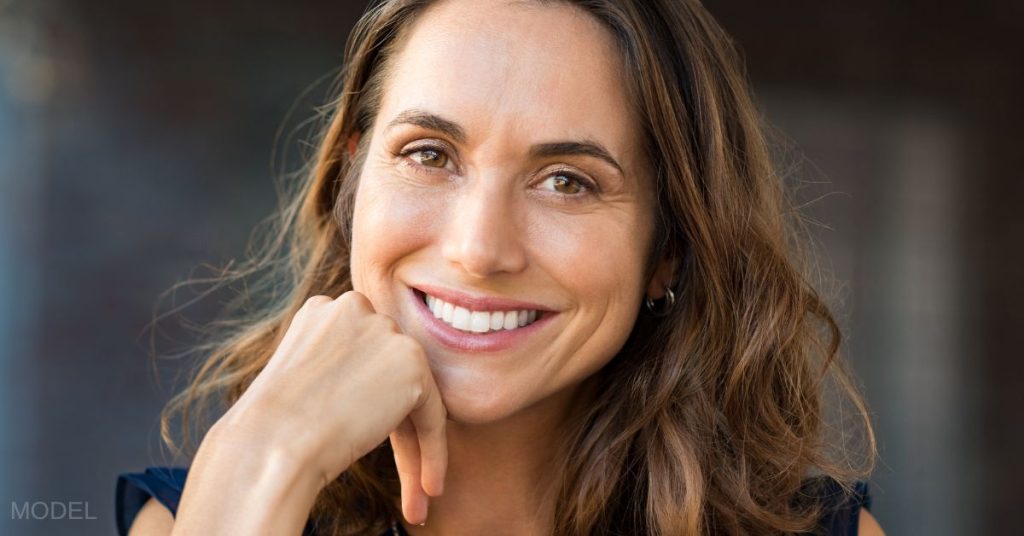 Woman smiling holding her head with her hand (MODEL)