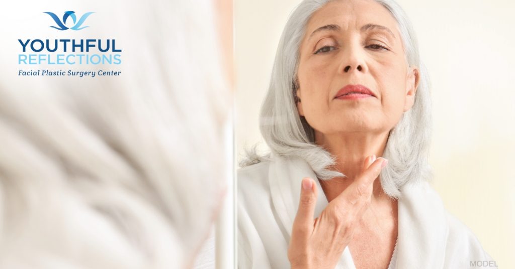 woman examining her healing facelift in the mirror (model)