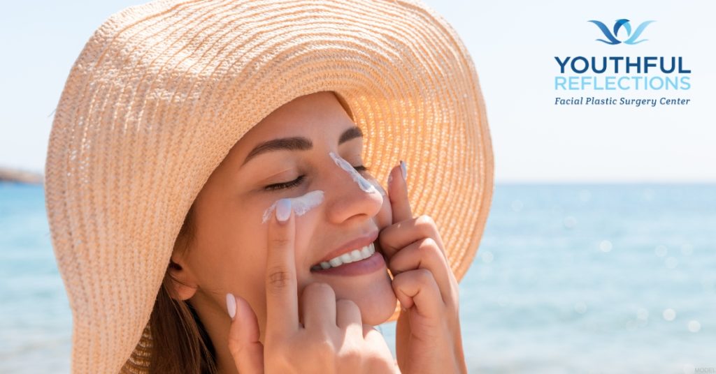 Woman applying sunscreen to her face (MODEL)