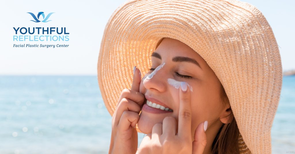 Woman applying sunscreen to her face (MODEL)