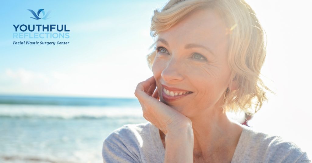 Woman smiling on the beach with the ocean in the background (model) Youthful Reflections: Michael A. Boggess, MD Logo