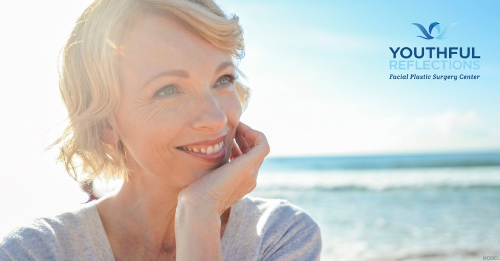 Woman smiling on the beach with the ocean in the background (model) Youthful Reflections: Michael A. Boggess, MD Logo